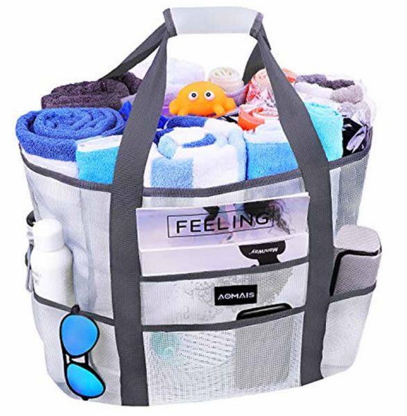 White durable mesh beach bag filled with several rolled beach towels and pool toys. Six exterior pockets holding sunglasses, phone, lotion...